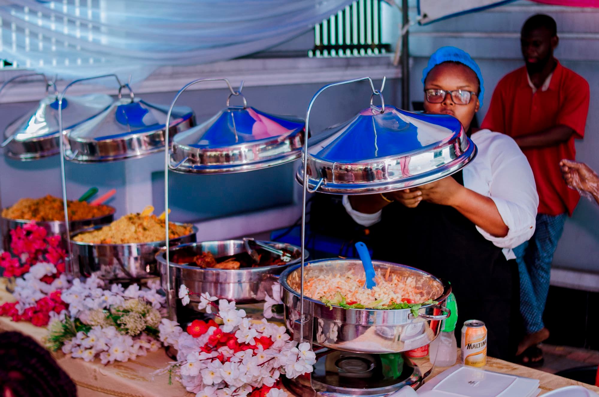 A caterer lifting the lid of a serving dish at an event buffet
