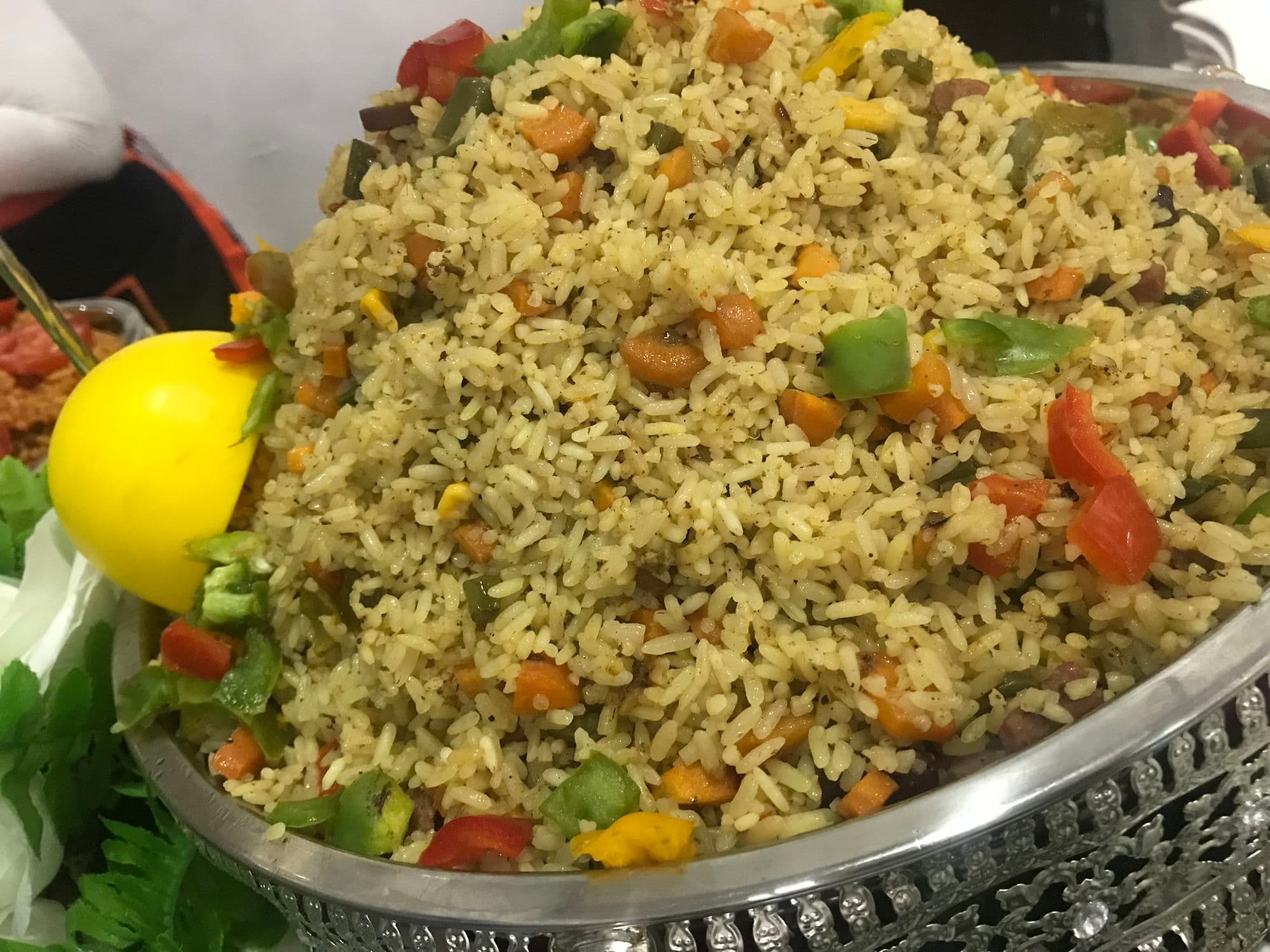 Nigerian fried rice with peppers and vegetables on a silver platter