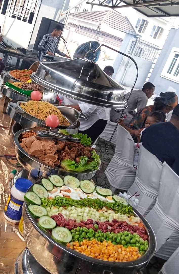 An outdoor buffet with salads, grilled meat and rice